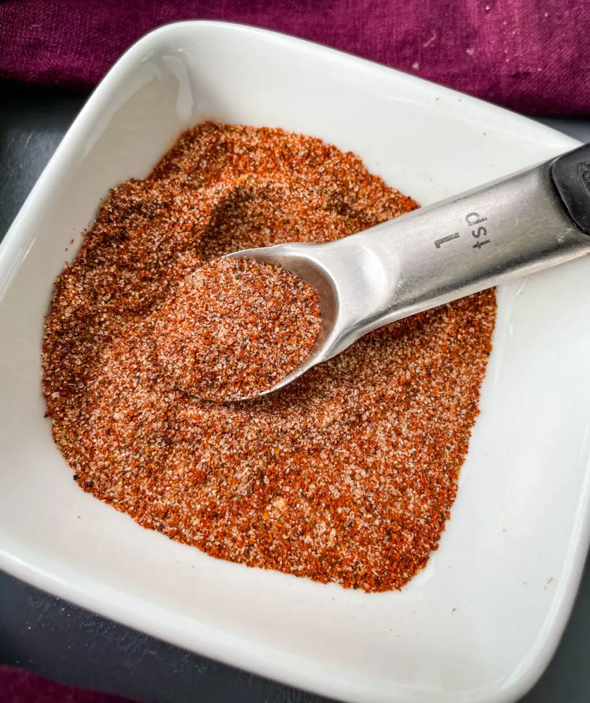 spices for chicken dry rub in a white bowl with a spoon