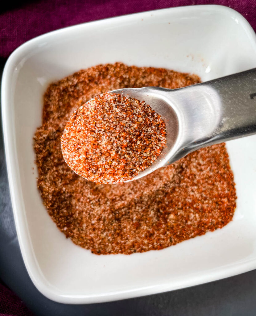 spices for chicken dry rub in a white bowl with a spoon