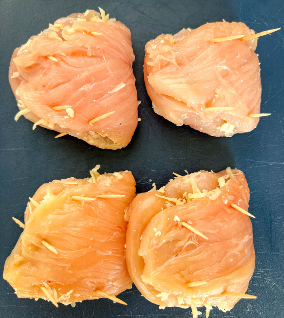 uncooked breaded stuffed mozzarella chicken breast on a cutting board