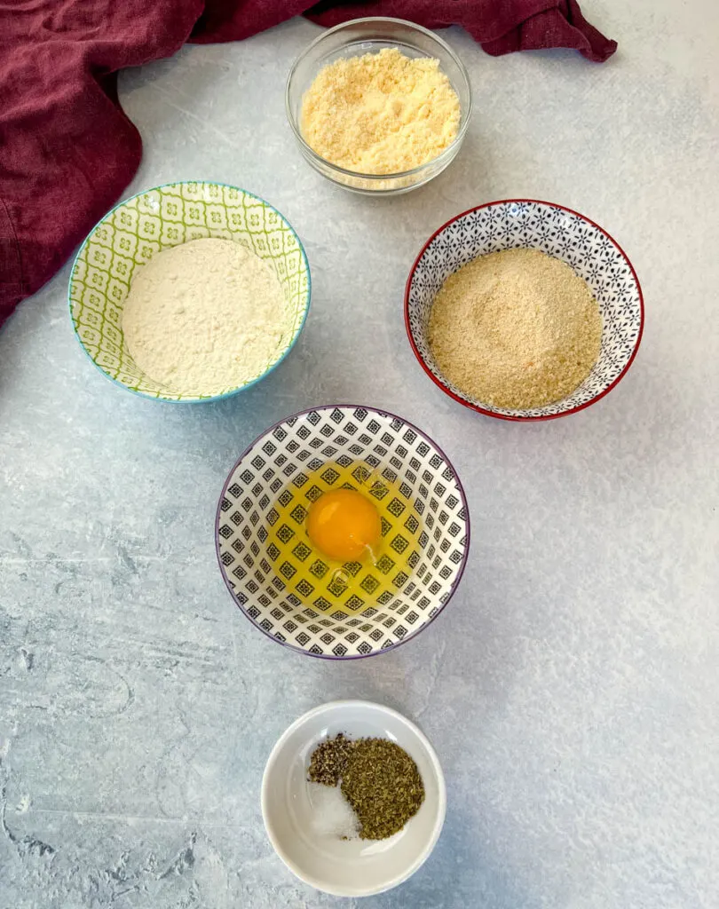 breadcrumbs, flour, egg, spices, and Parmesan cheese in separate bowls