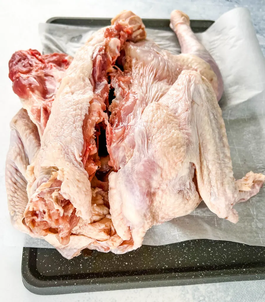 raw turkey with backbone removed on parchment paper
