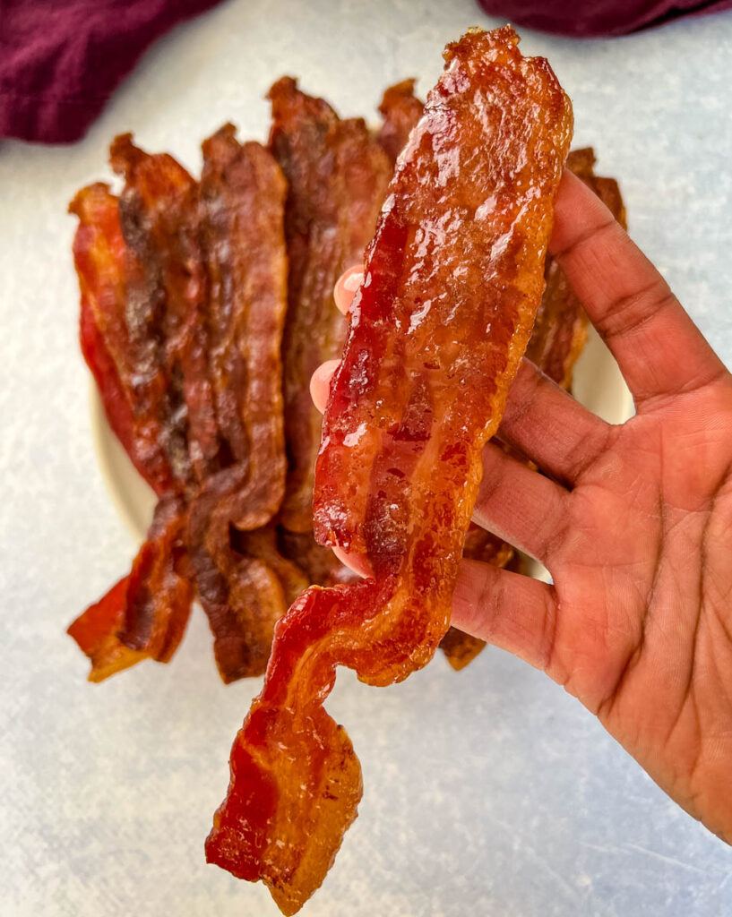 person holding a piece of smoked bacon