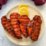 Traeger smoked chicken breasts on a plate with lemons