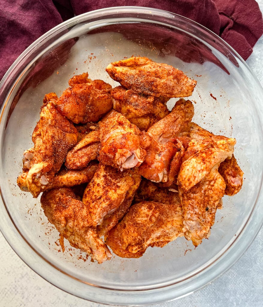 raw chicken wings in a glass bowl with spices