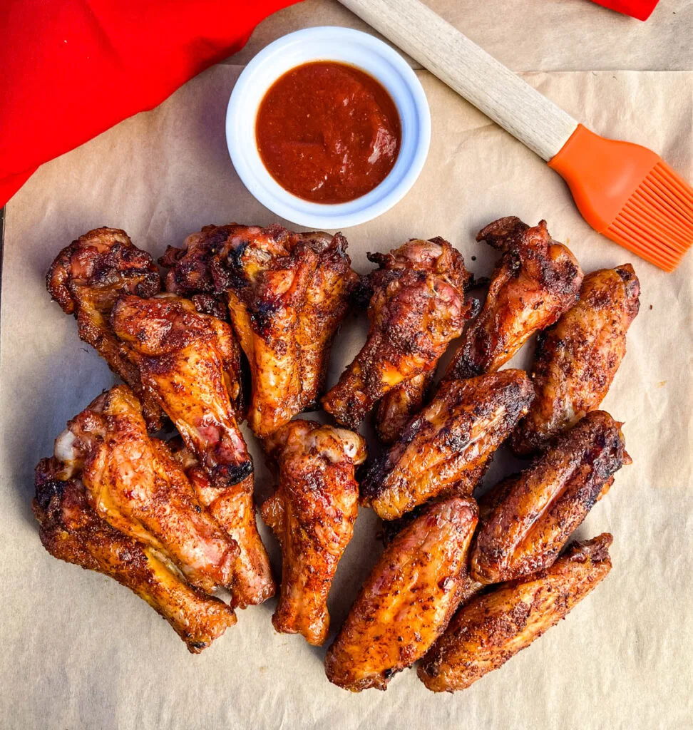 Traeger smoked chicken wings on a plate with BBQ sauce