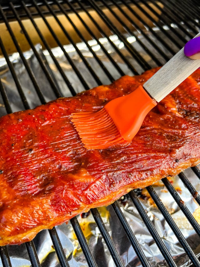 BBQ sauce drizzled onto rib on Traeger smoker