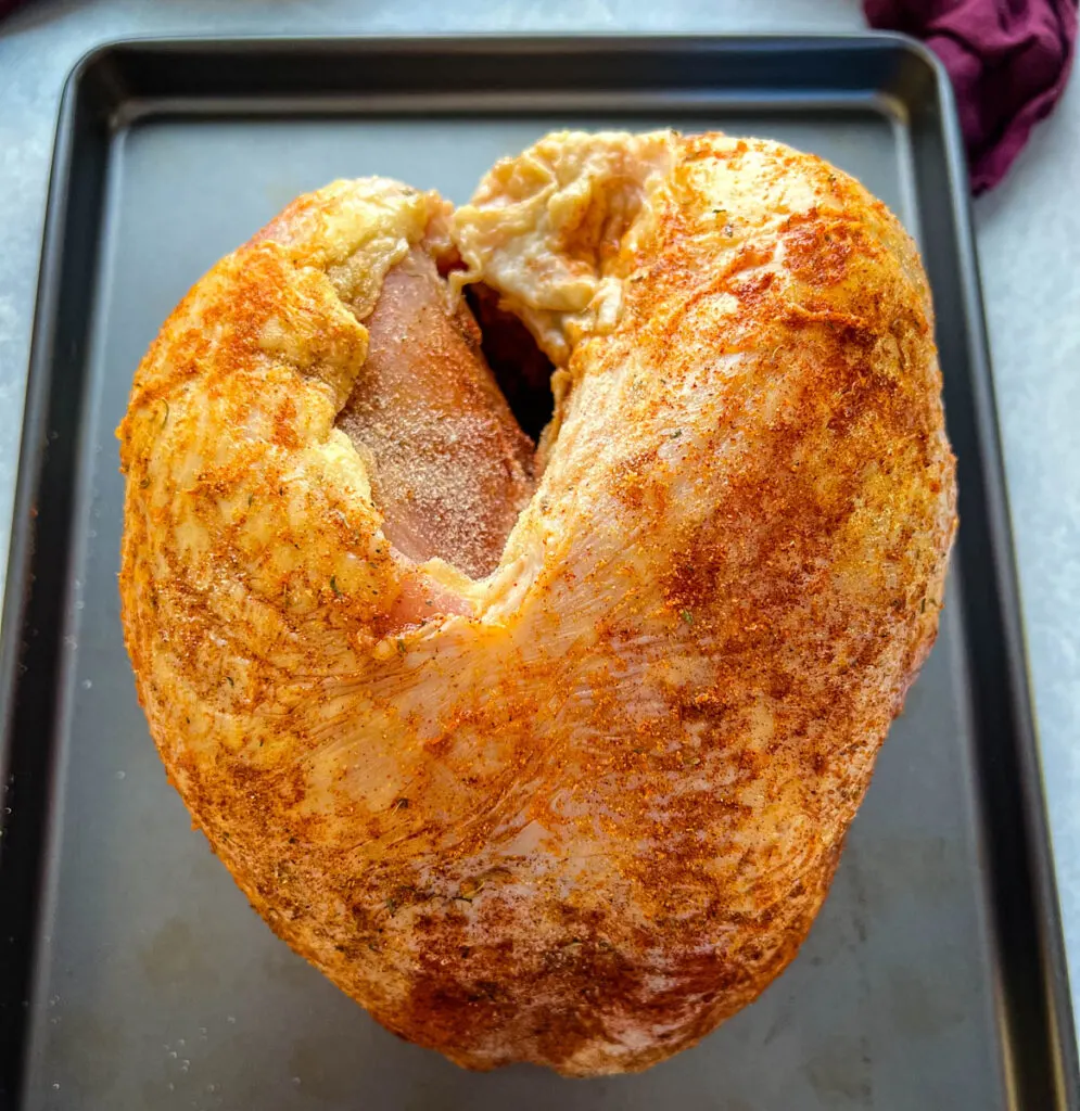 raw seasoned turkey breast on a pan