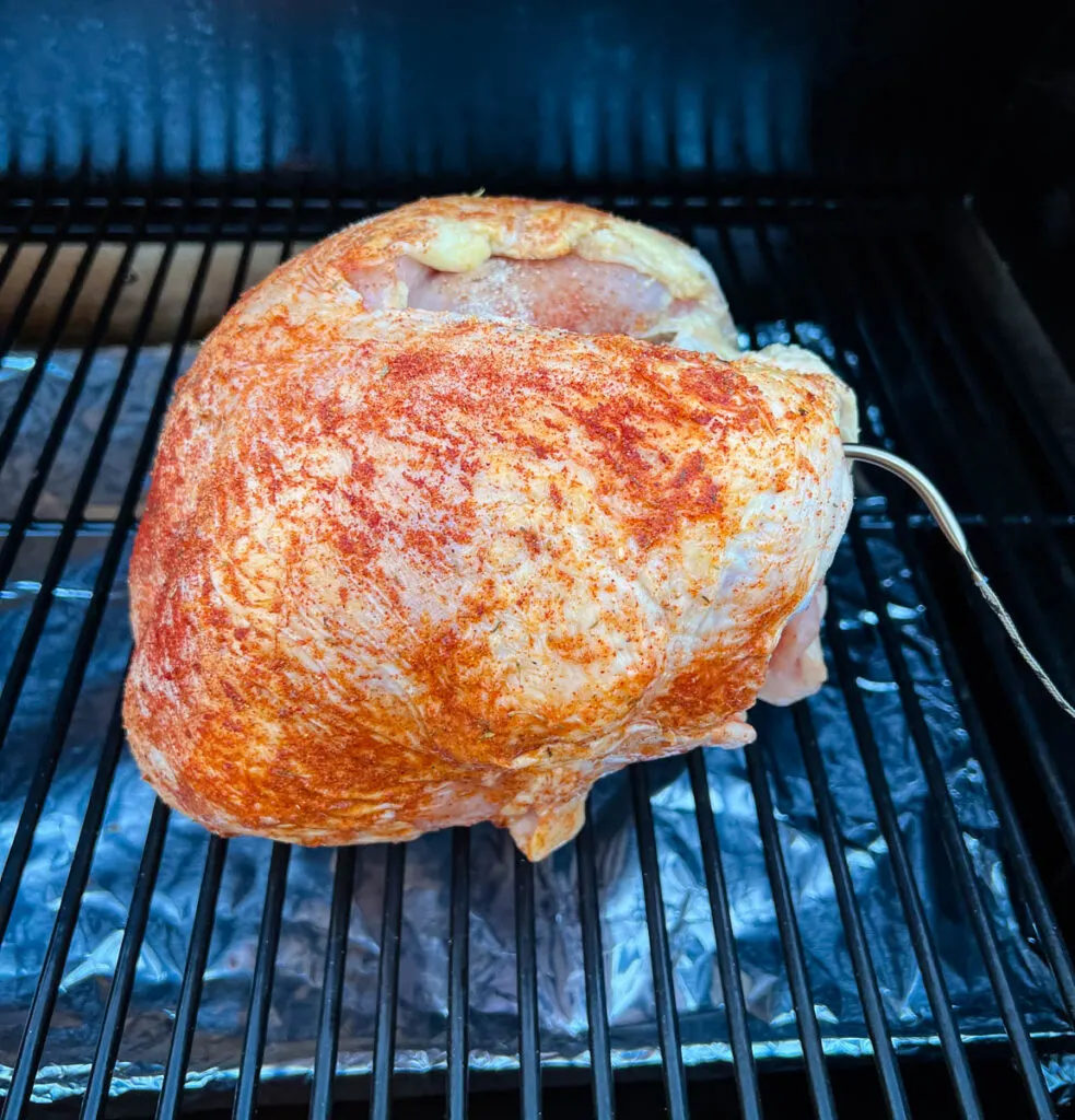 raw seasoned turkey breast in a Traeger grill