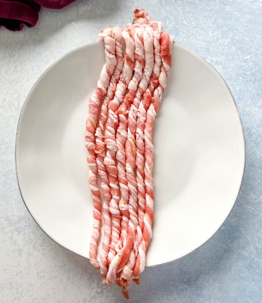 uncooked twisted bacon on a white plate