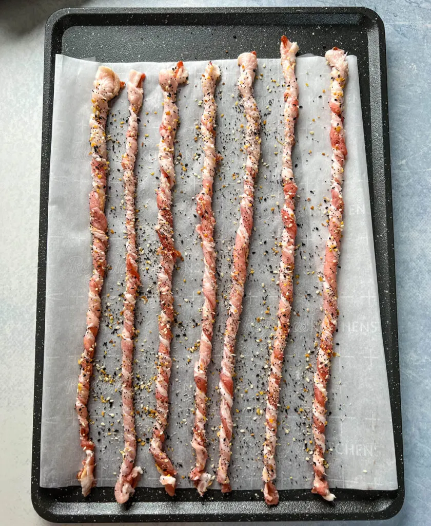 twisted bacon on a sheet pan seasoned with Everything But the Bagel Seasoning