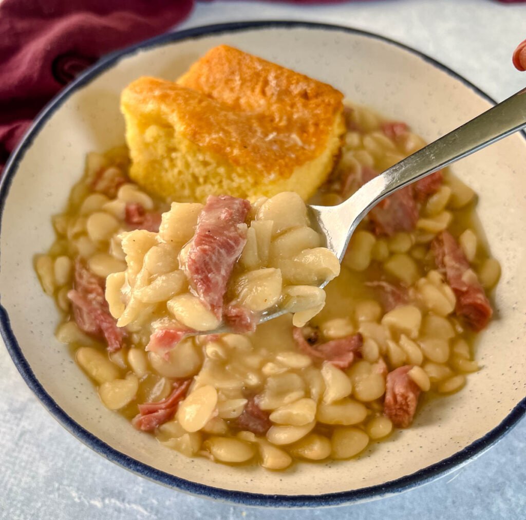 a spoonful of Southern butter lima beans in a bowl with cornbread