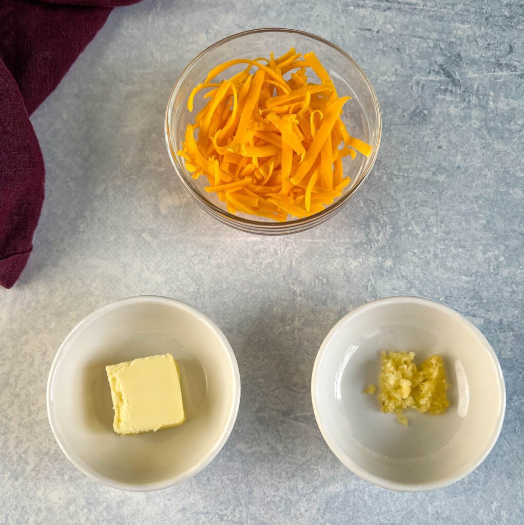 shredded cheese, butter, and garlic in separate bowls