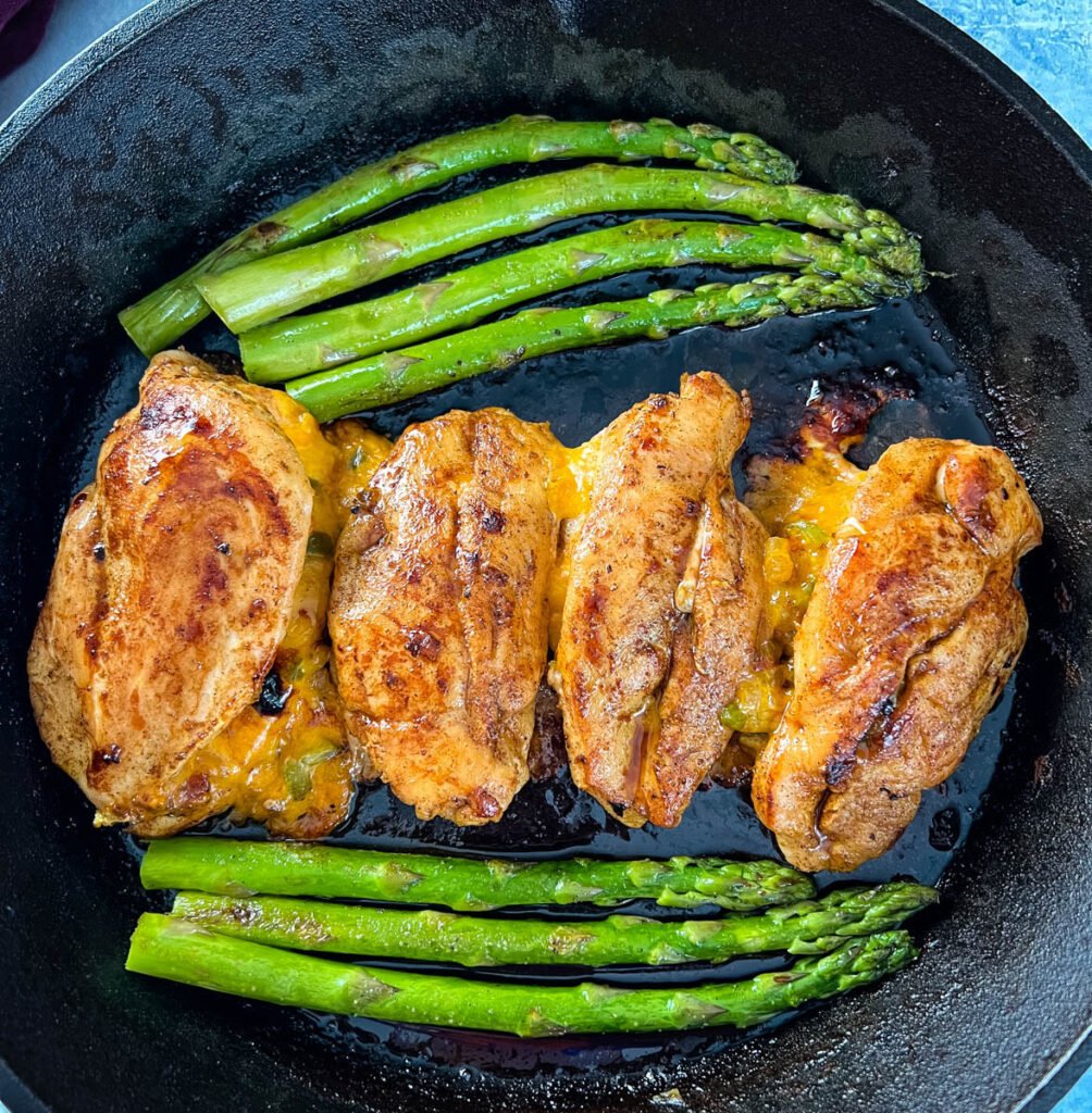 oven stuffed chicken breast in a cast iron skillet with asparagus