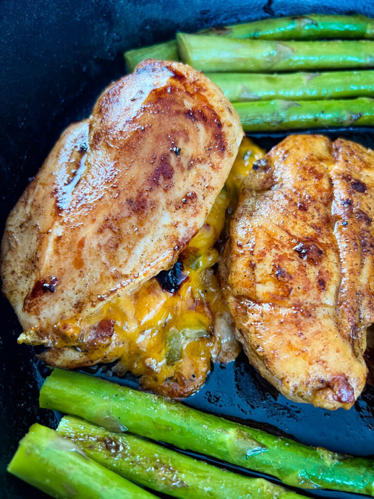 oven stuffed chicken breast in a cast iron skillet with asparagus