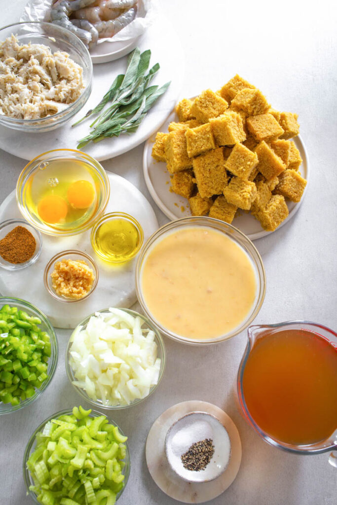 cooked cornbread, vegetables, broth, and seafood in separate bowls