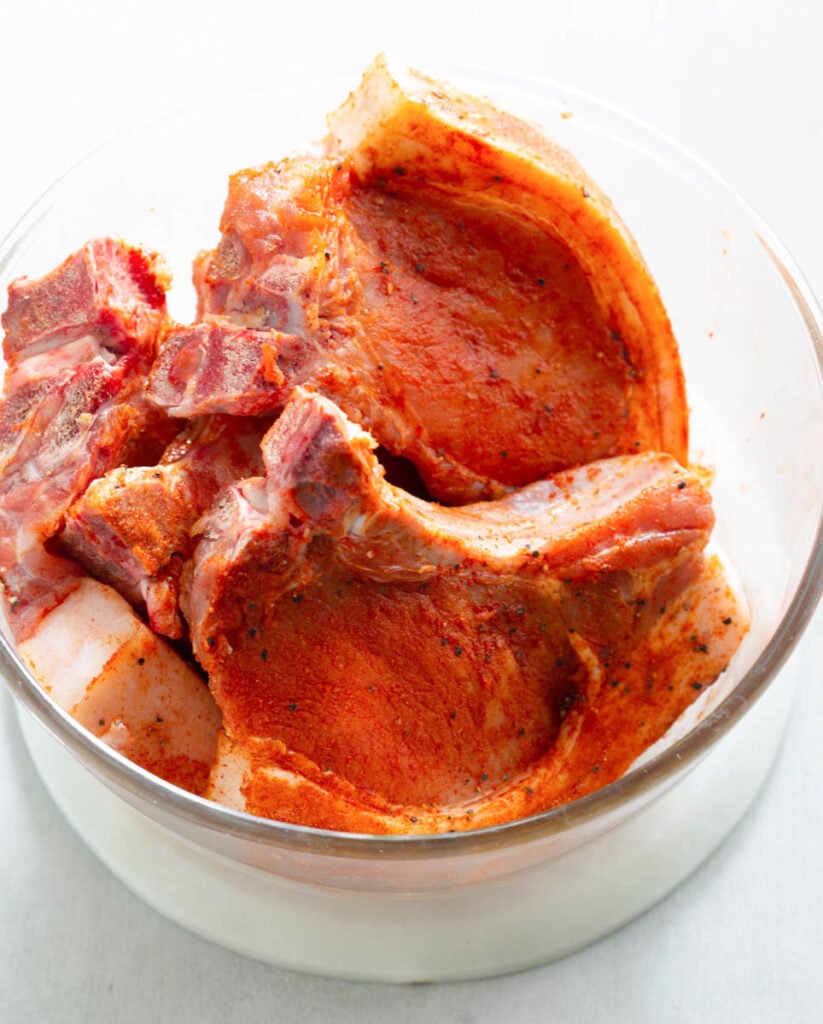 raw seasoned pork chops in a glass bowl