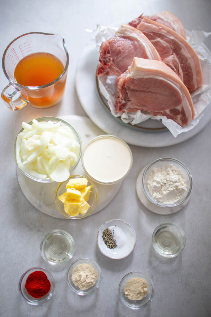 raw pork chops, onions, cream, broth, garlic, spices, and flour in separate bowls