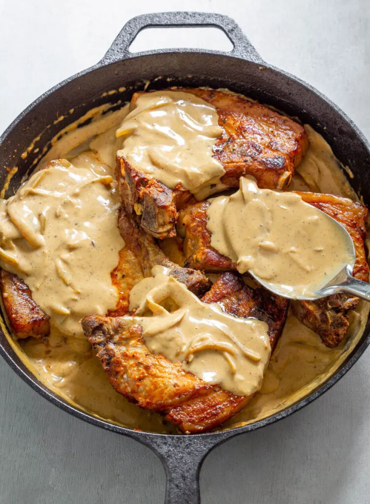 southern smothered pork chops in a cast iron skillet with gravy