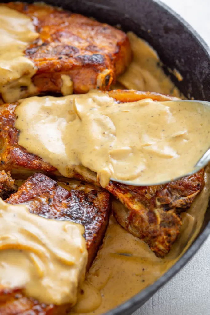 southern smothered pork chops in a cast iron skillet with gravy