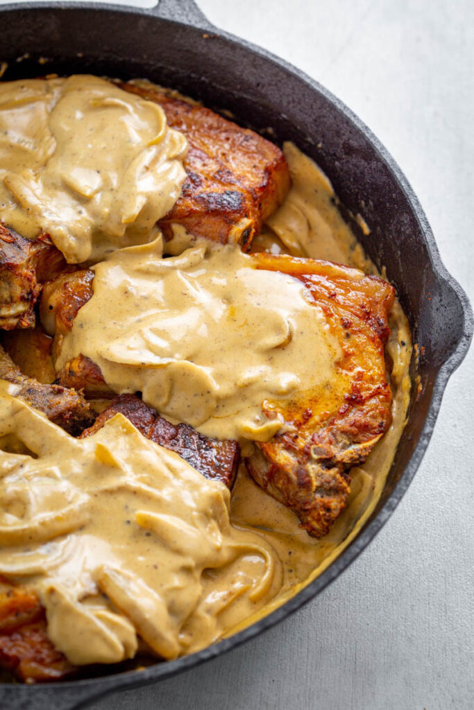 southern smothered pork chops in a cast iron skillet with gravy