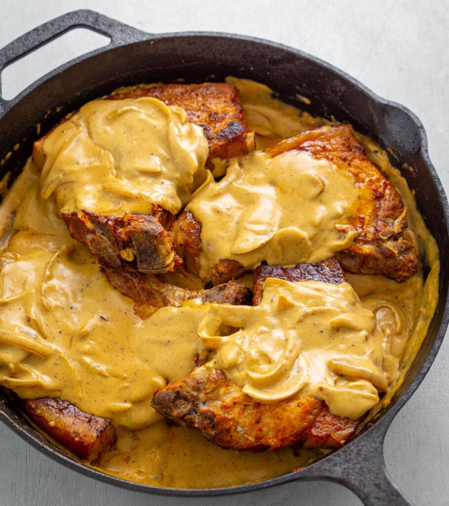 southern smothered pork chops in a cast iron skillet with gravy