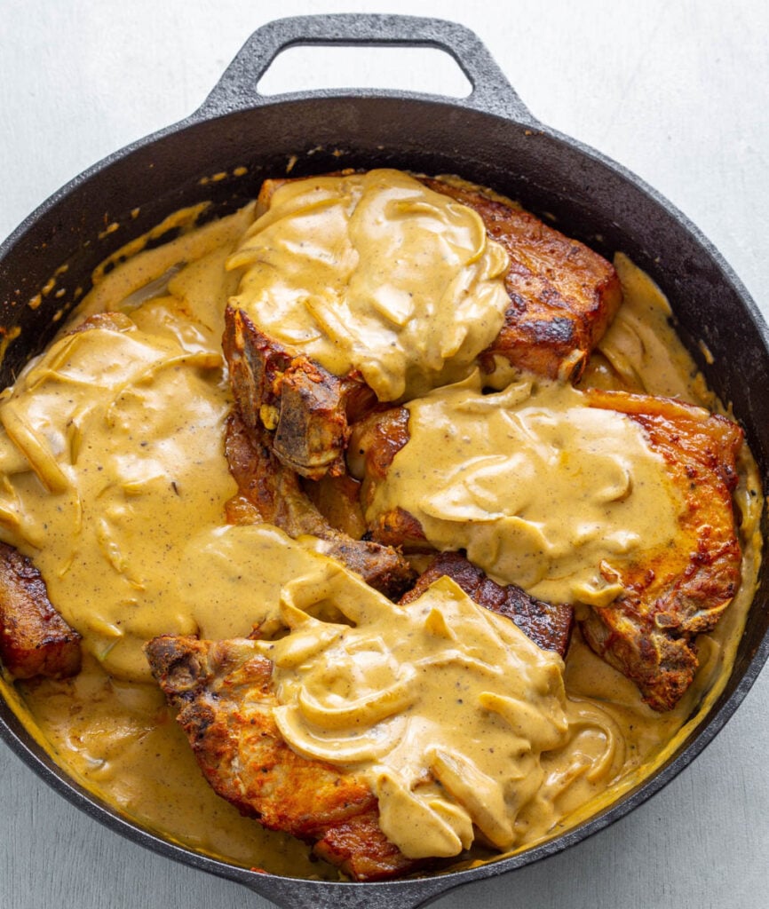 southern smothered pork chops in a cast iron skillet with gravy