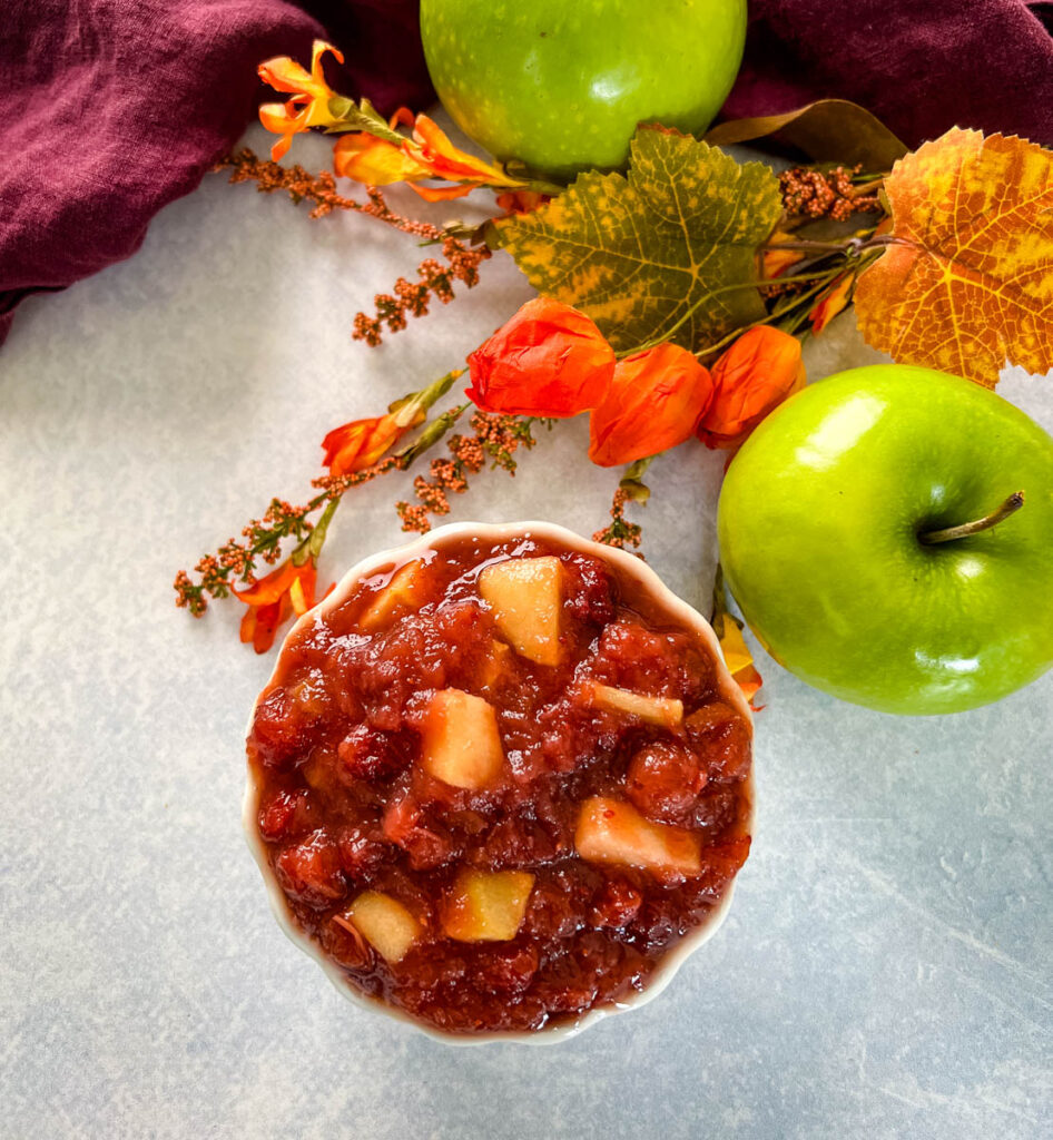 apple cranberry sauce in a white bowl with a fresh apple