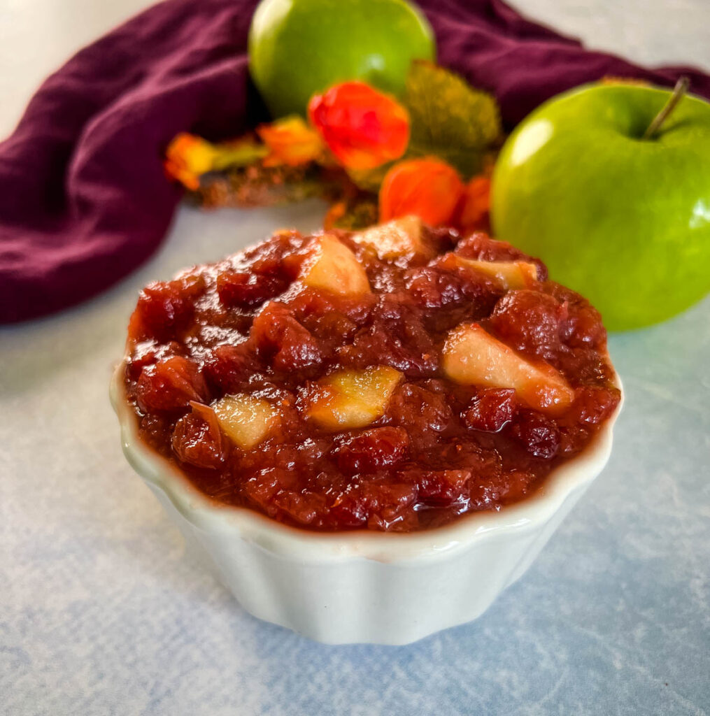 apple cranberry sauce in a white bowl with a fresh apple