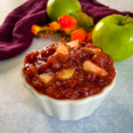 apple cranberry sauce in a white bowl with a fresh apple