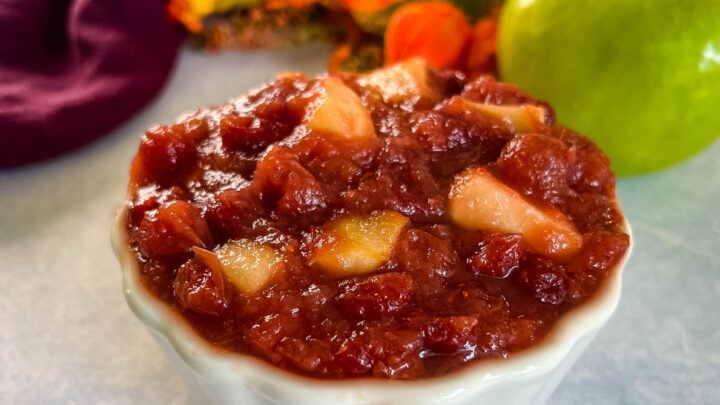 apple cranberry sauce in a white bowl with a fresh apple