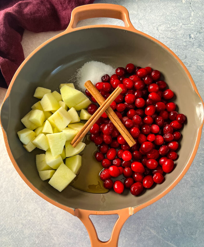 apples, cranberries, honey, cinnamon sticks, and sugar in a skilet