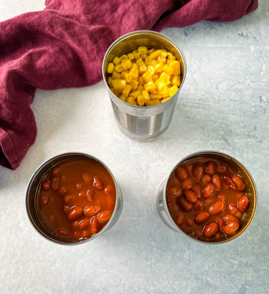 canned corn and canned beans on a flat surface