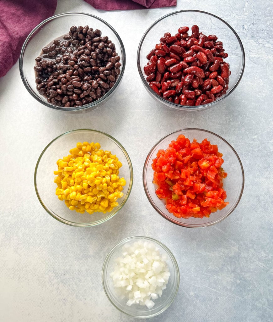 corn, beans, onion, tomatoes, and garlic in separate bowls