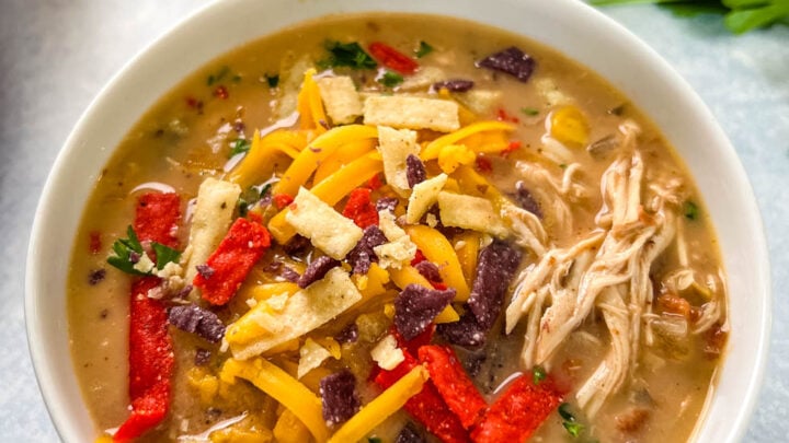 slow cooker chicken taco soup in a white bowl with tortilla strips and cheese