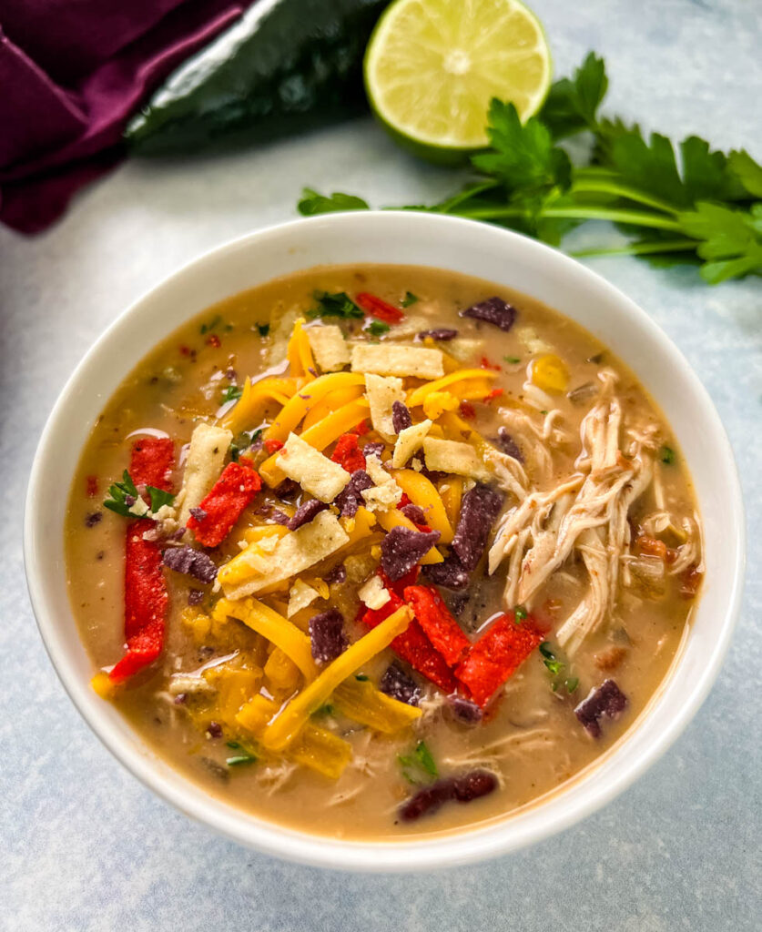 slow cooker chicken taco soup in a white bowl with tortilla strips and cheese