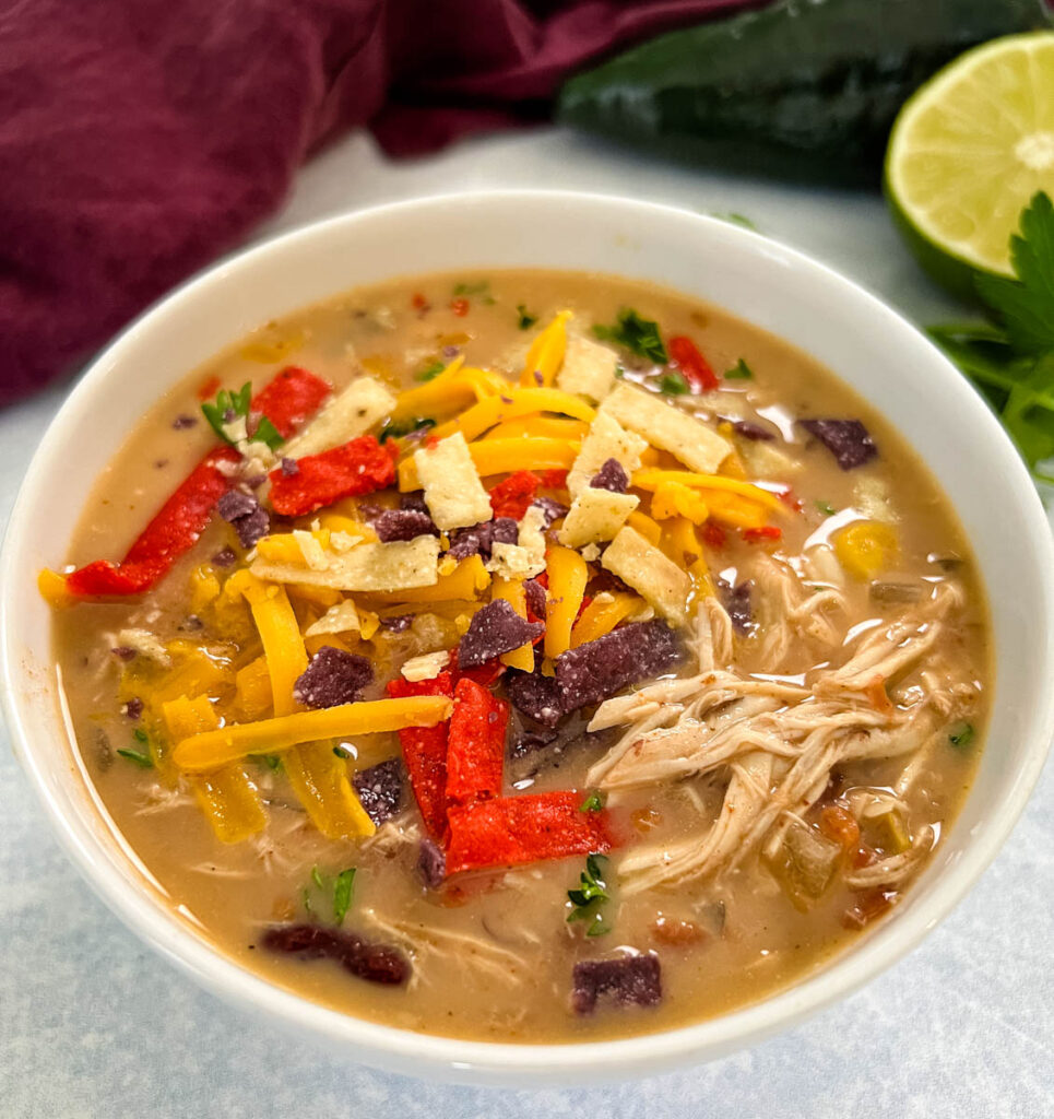 slow cooker chicken taco soup in a white bowl with tortilla strips and cheese