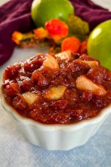 apple cranberry sauce in a white bowl with a fresh apple