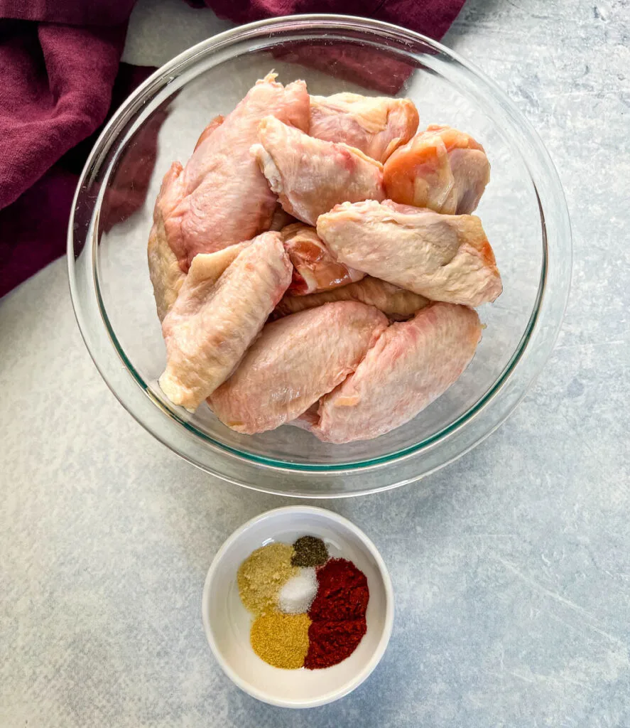 raw chicken wings and spices in separate bowls