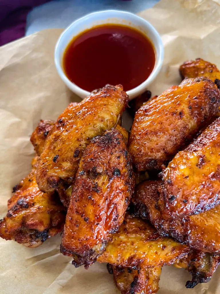 honey hot wings on a plate with hot sauce