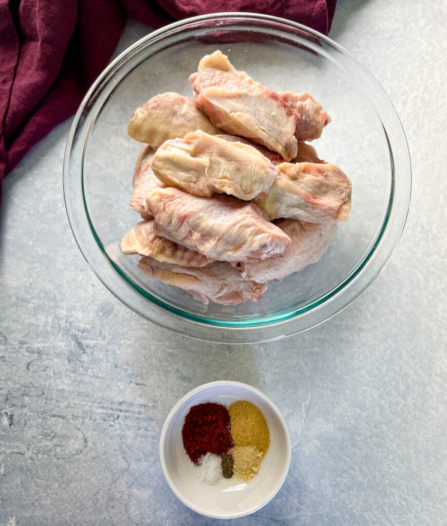 raw chicken wings and spices in separate bowls