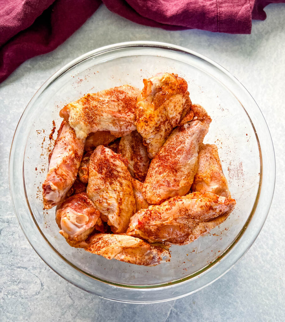 raw seasoned chicken wings in a glass bowl