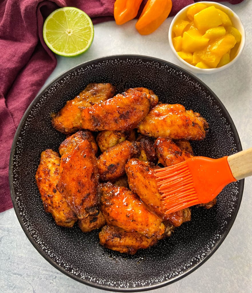 mango habanero wings in a black bowl brushed with sauce