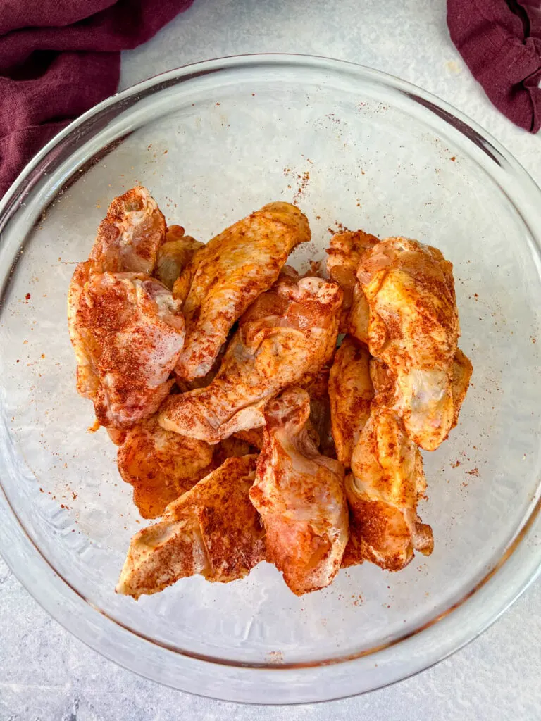 raw seasoned chicken wings in a glass bowl