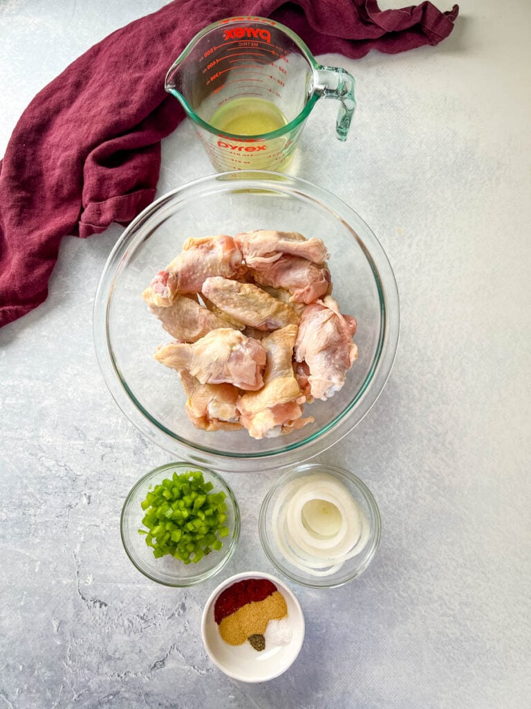 raw chicken wings, broth, fresh green peppers, onions, and spices in separate bowls