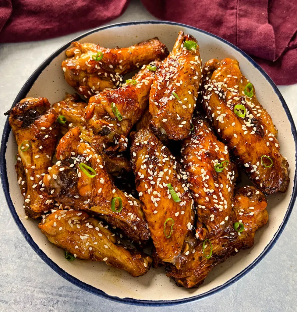 teriyaki chicken wings in a white and blue bowl with sesame seeds