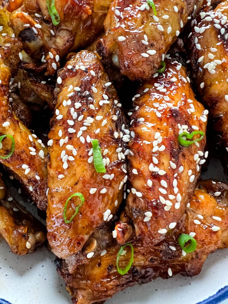 teriyaki chicken wings in a white and blue bowl with sesame seeds