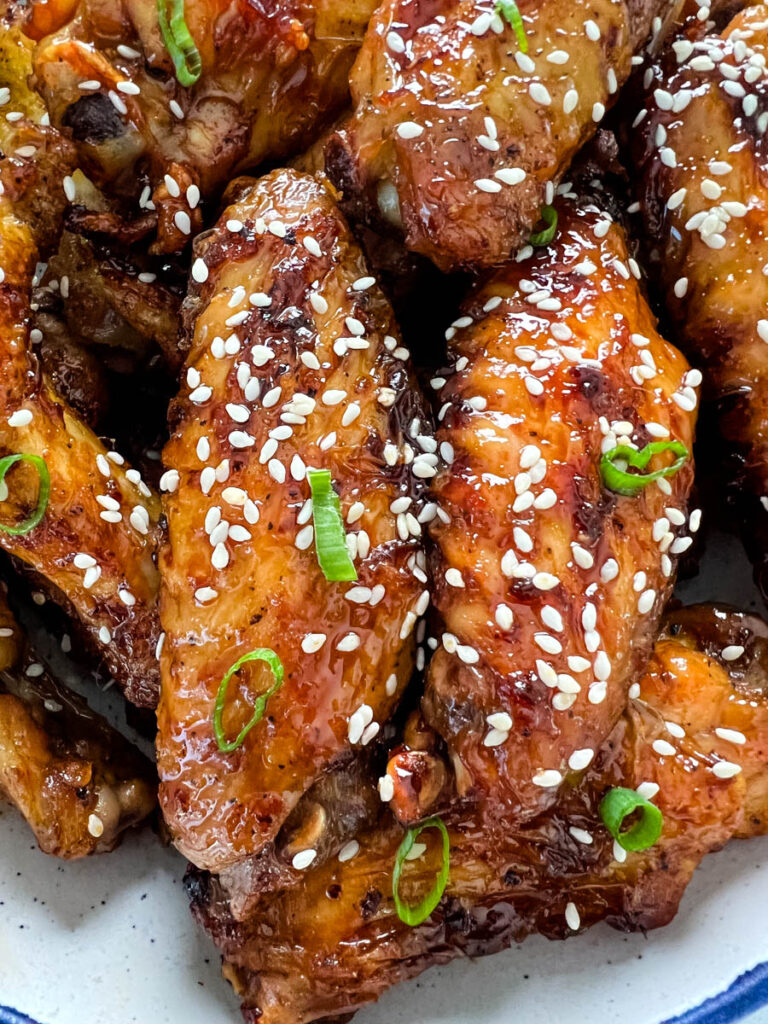 teriyaki chicken wings in a white and blue bowl with sesame seeds