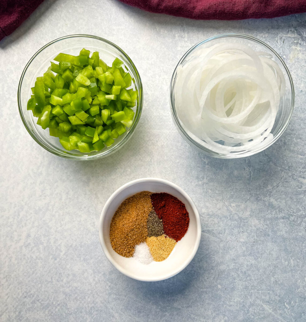 chopped green peppers, sliced onions, and spices in separate bowls