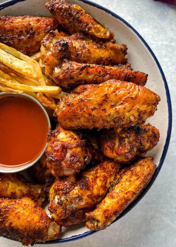 Cajun chicken wings in a bowl with french fries