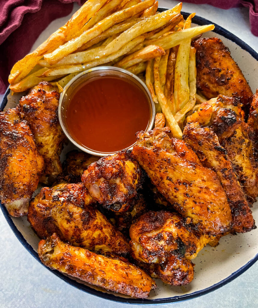 Cajun chicken wings in a bowl with french fries